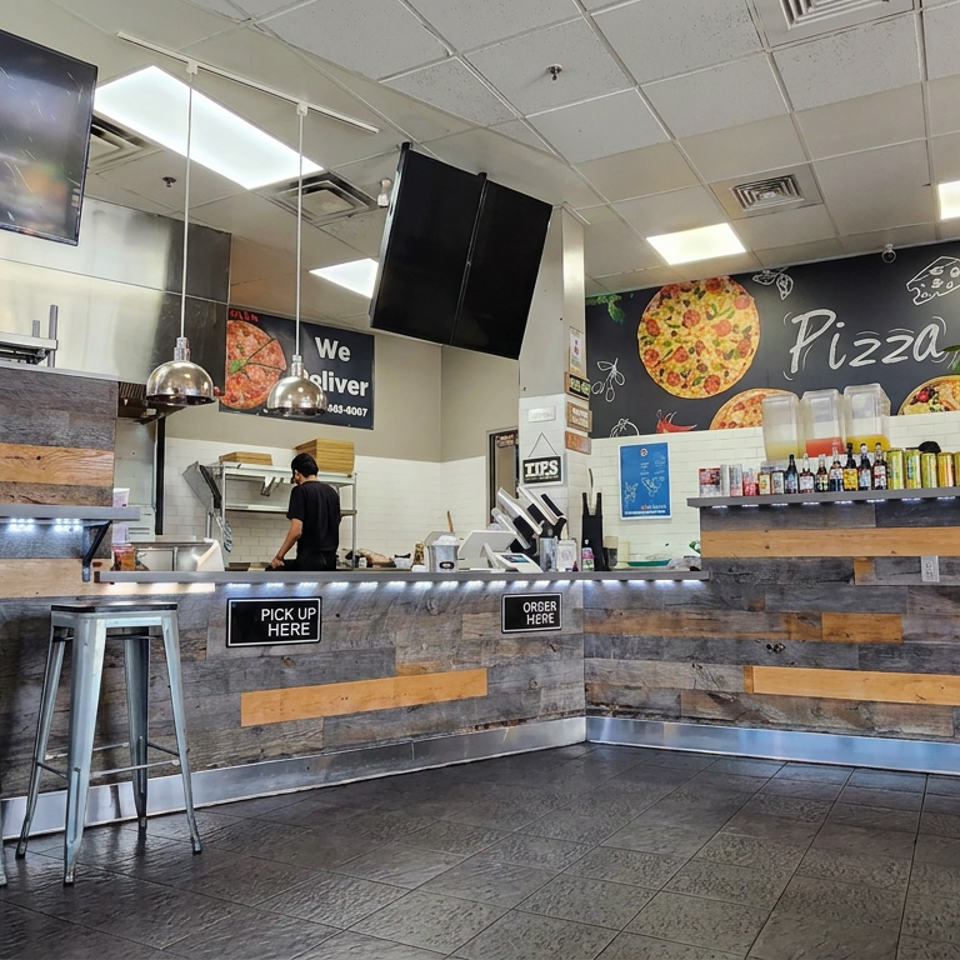 Pizza restaurant counter with rustic wood paneling, soda fountain, stools, pickup and order signs, and a staff member preparing food.